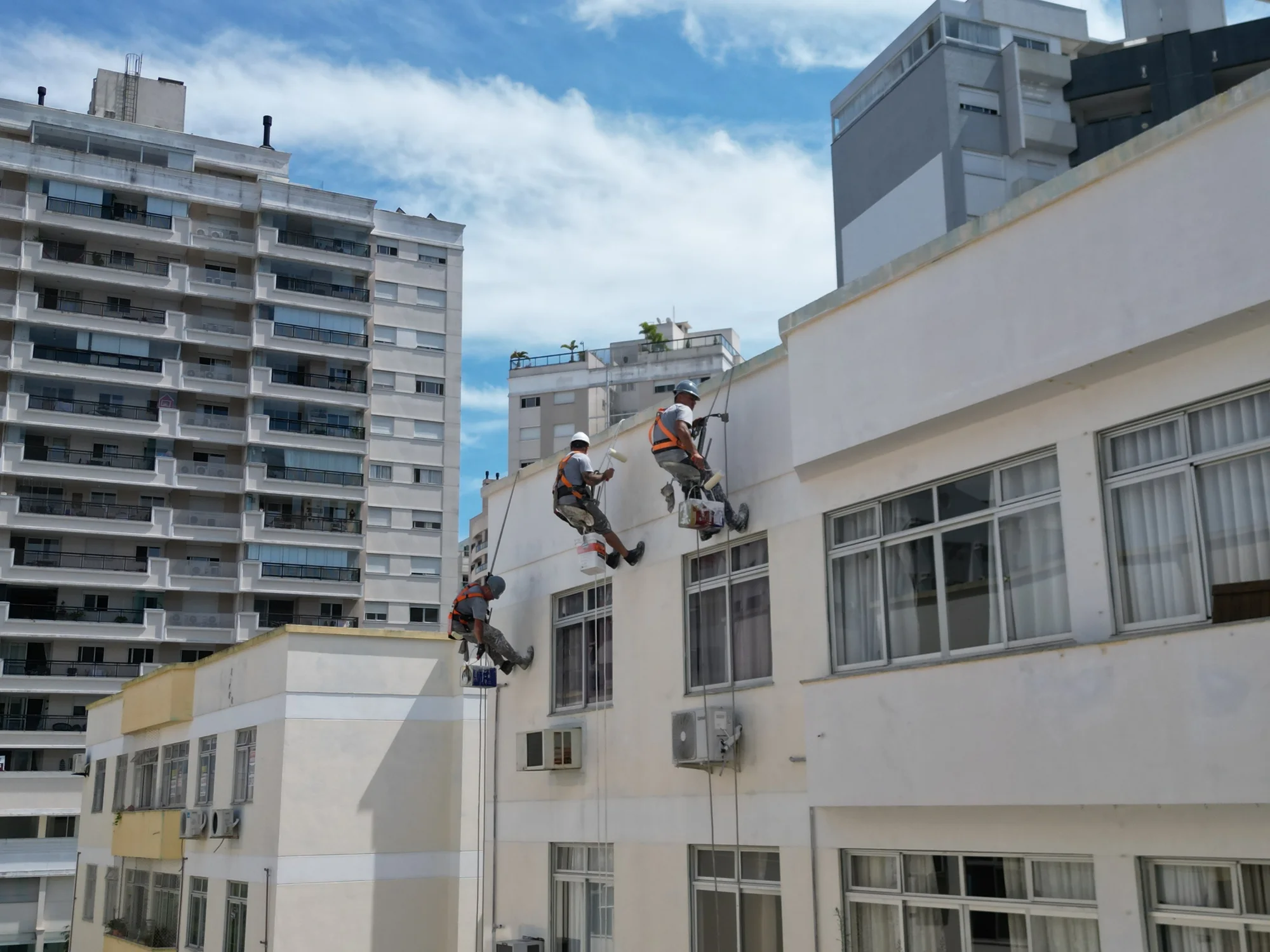 Equipe Restaura executando pintura em altura na fachada de um condomínio